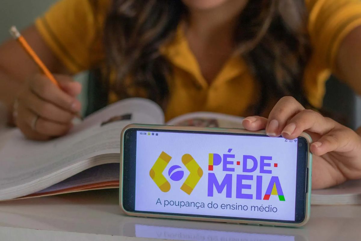 foto de estudante com celular aberto na logo do programa pé-de-meia