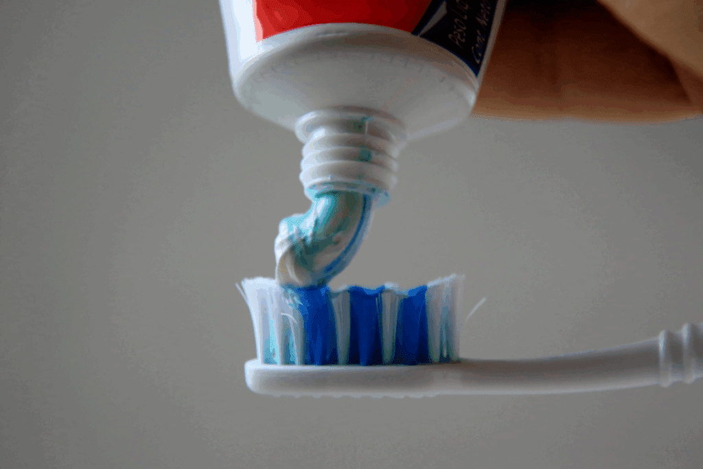 foto de pasta de dente clean mint da colgate sendo colocada em escova de dente
