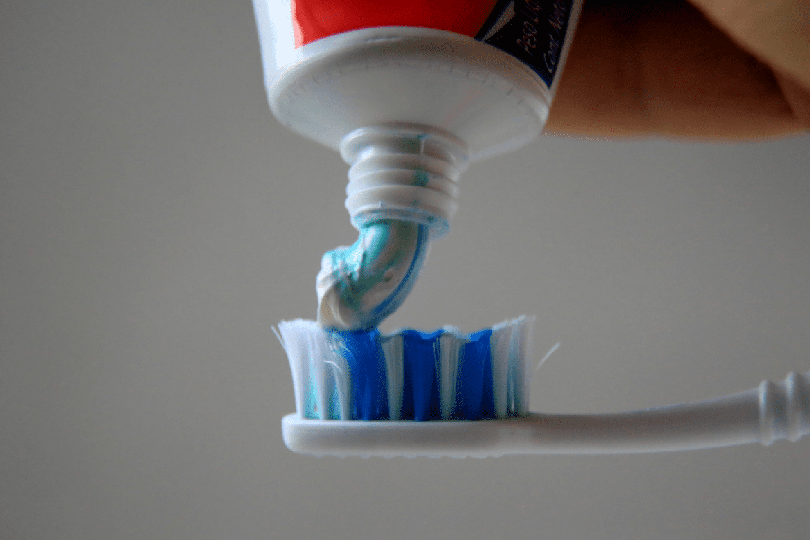 foto de pasta de dente clean mint da colgate sendo colocada em escova de dente