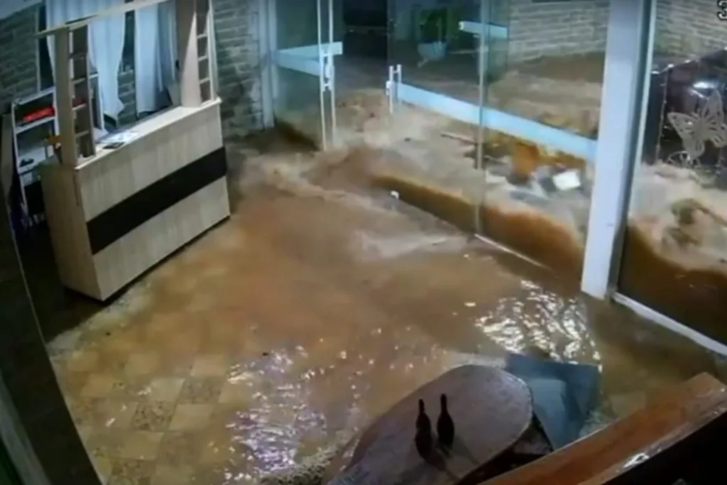 Cadeiras e uma mesa de madeira podem ser vistos enquanto são levados pela água. (Foto: Captura)