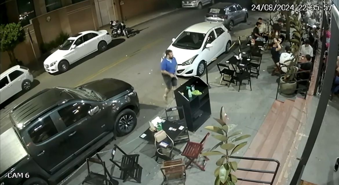 Suspeito, de camiseta de cor azul, foi flagrado com a arma falsa na entrada do bar (Foto: Captura)