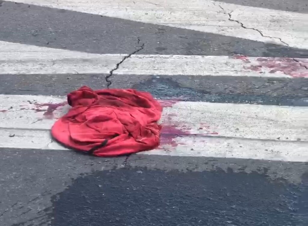 Roupas da vítima e manchas de sangue no asfalto (Foto: Victor Santos)