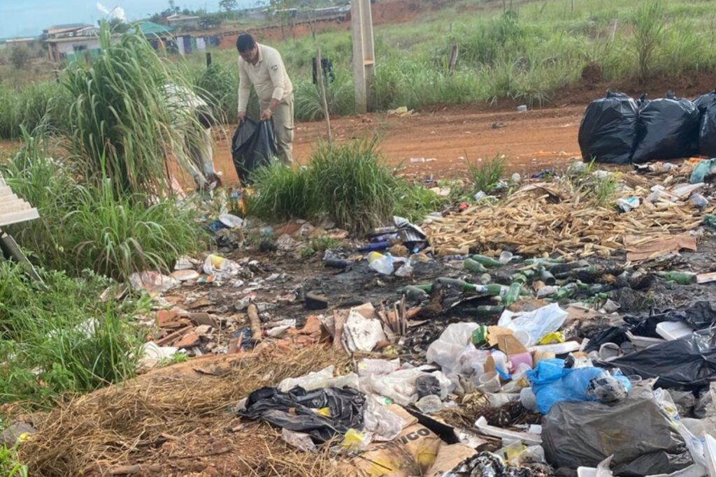 foto de agente de endemias realizando limpeza em área de descarte irregular