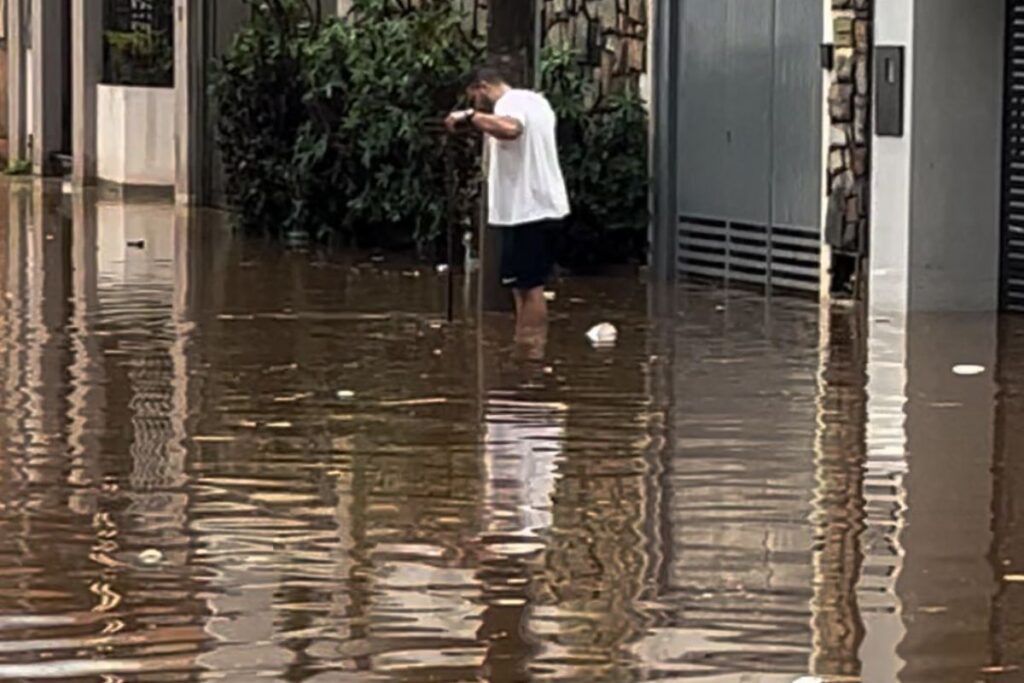 foto de homem tentando atravessar via alagada em Anápolis após chuvas